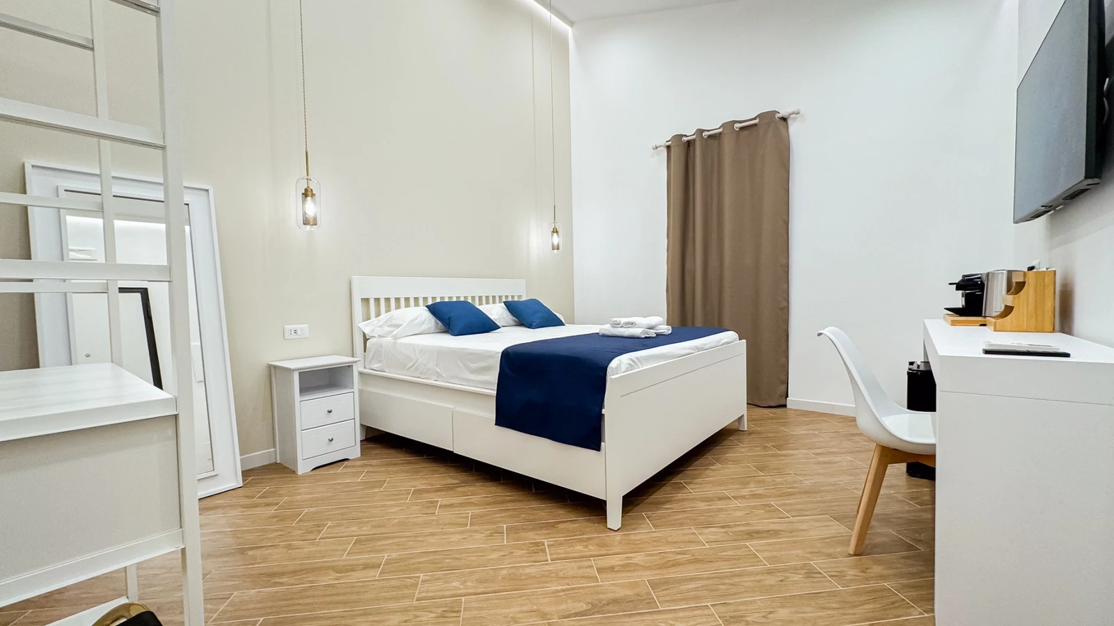 La camera Desdemona: letto matrimoniale con copriletto blu, scrivania e televisore